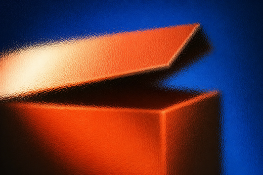 Unbranded rigid box with lifted lid seen through full-frame hammered glass in cobalt, coral and cream light.