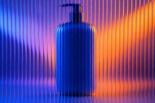 Unbranded large shampoo pump bottle behind textured glass in vivid coloured light.