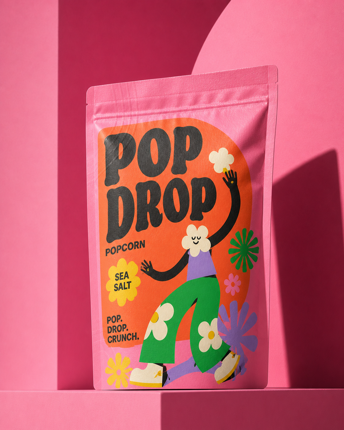 POP DROP Sea Salt popcorn stand-up pouch hero image with oversized black typography and playful character illustration on pink.