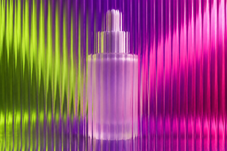 Unbranded frosted serum bottle behind textured glass in vivid coloured light.