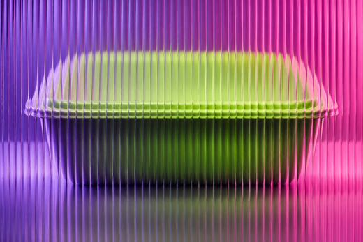 Unbranded meal tray behind textured glass in vivid coloured light.