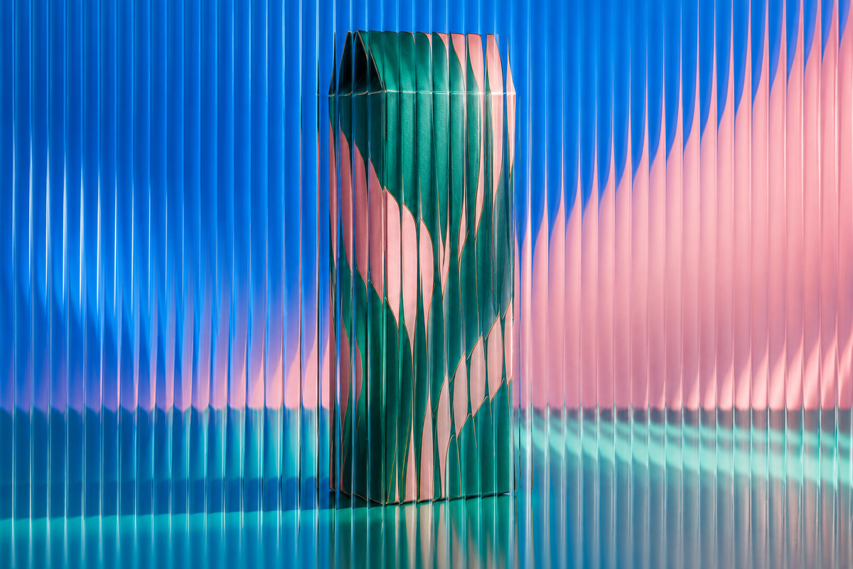 Unbranded tall confectionery carton behind textured glass in vivid coloured light.