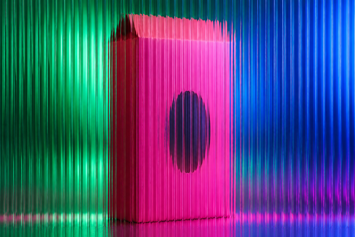 Pink food carton with an oval window behind fluted glass in green and blue light.