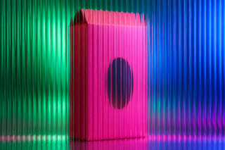 Pink food carton with an oval window behind fluted glass in green and blue light.