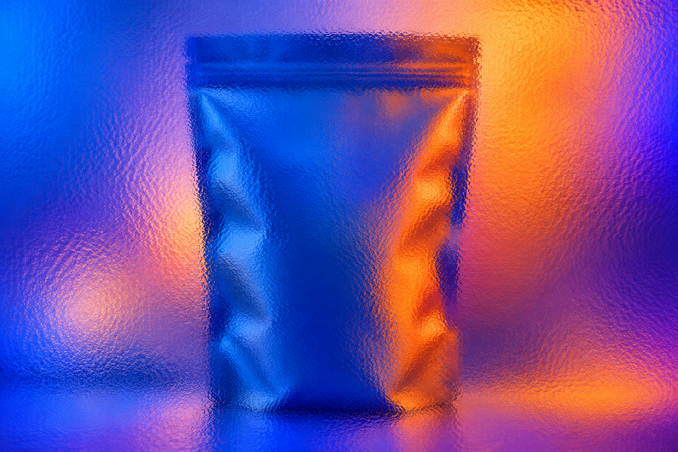 Unbranded food pouch behind textured glass in cobalt, orange and violet light.