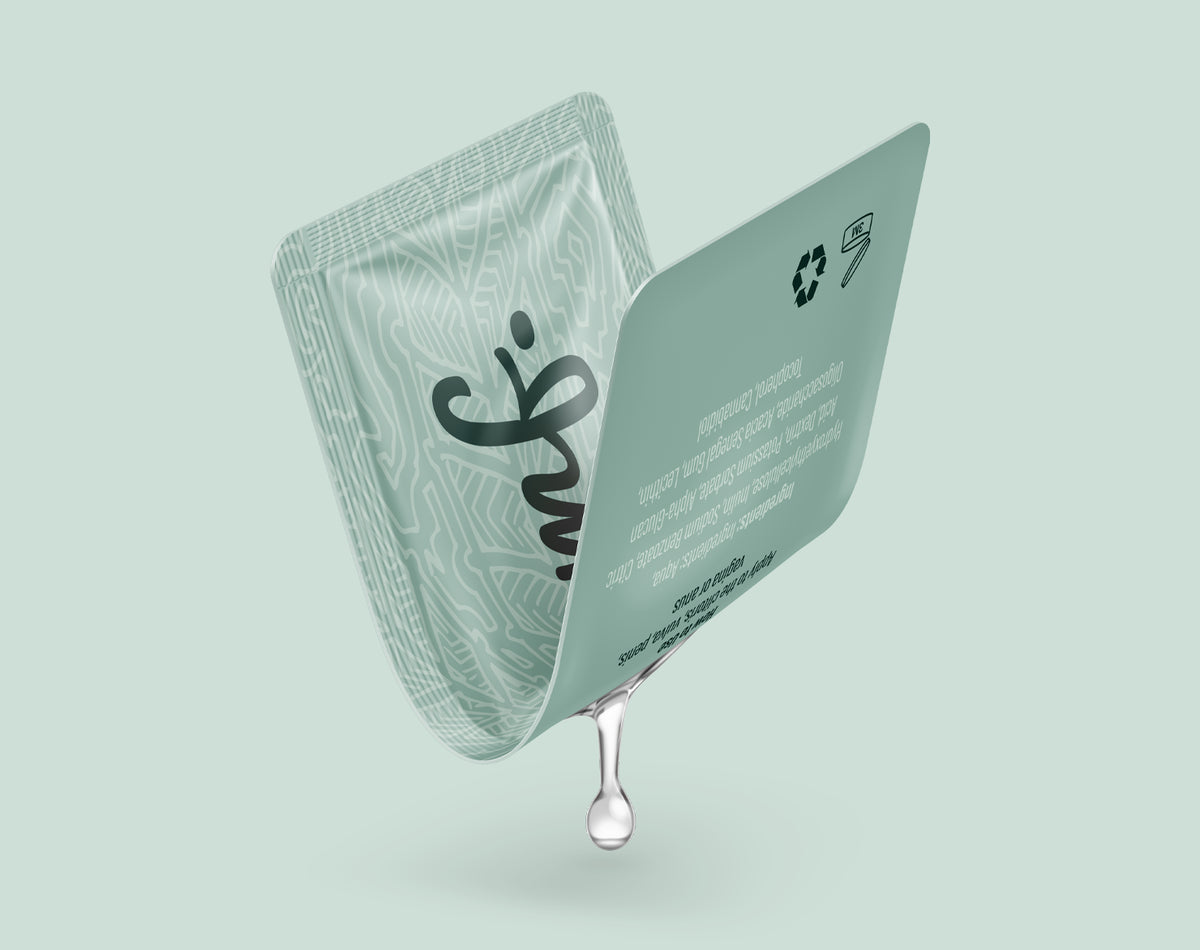 Opened OOMF personal lubricant sachet with a liquid drop, demonstrating the single-use flexible packaging format.