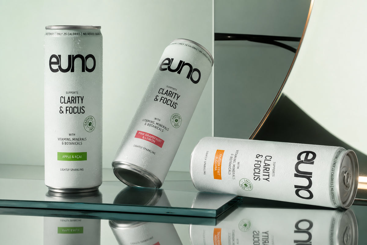 Three Euno caffeine-free functional drink cans photographed on polished chrome in a minimalist fashion editorial composition