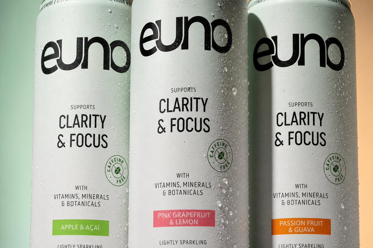Macro product photograph of the Euno functional drink range showing condensation, aluminium detail and green, coral and orange flavour coding
