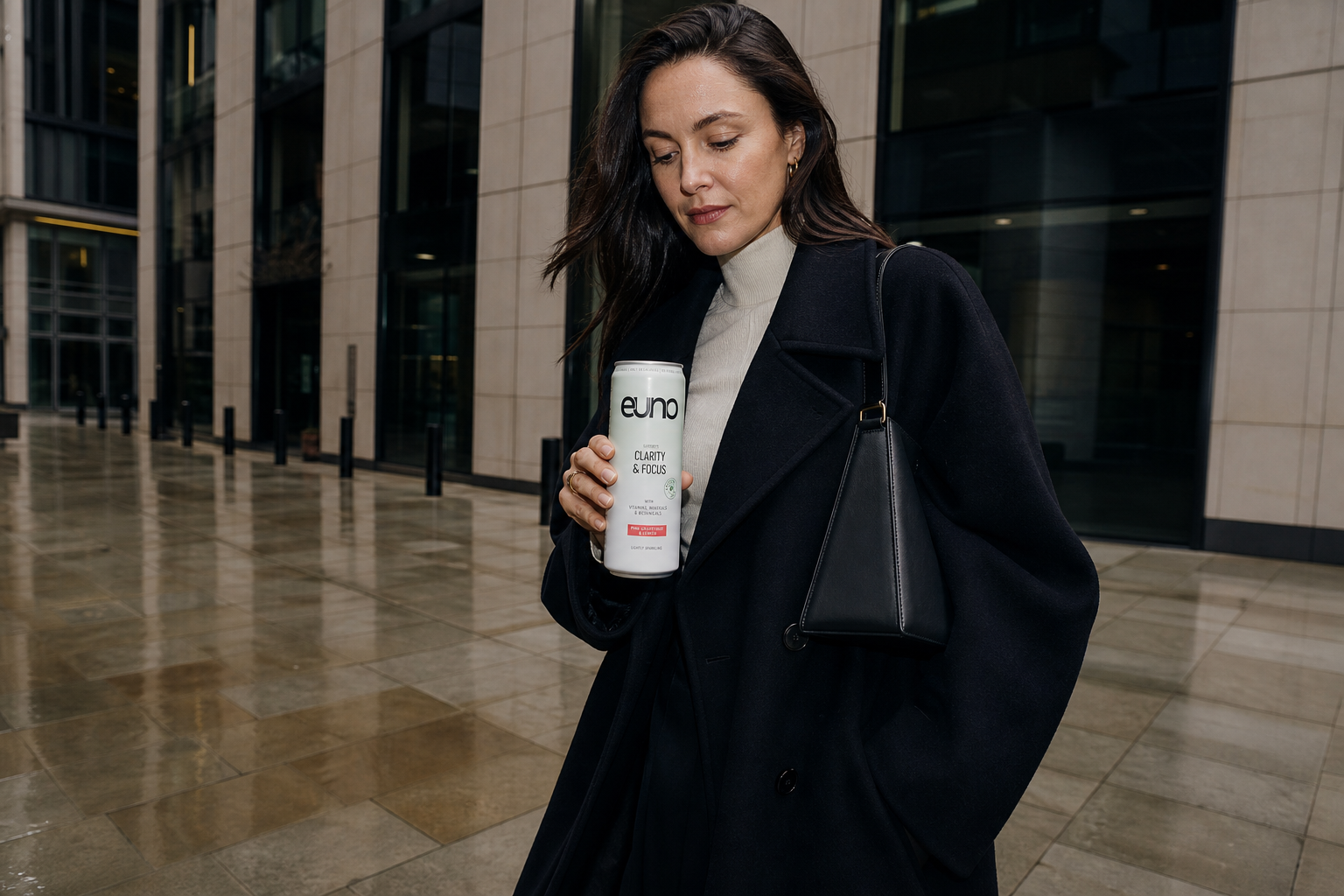 Stylish professional woman carrying an Euno caffeine-free focus drink outside contemporary Central London offices