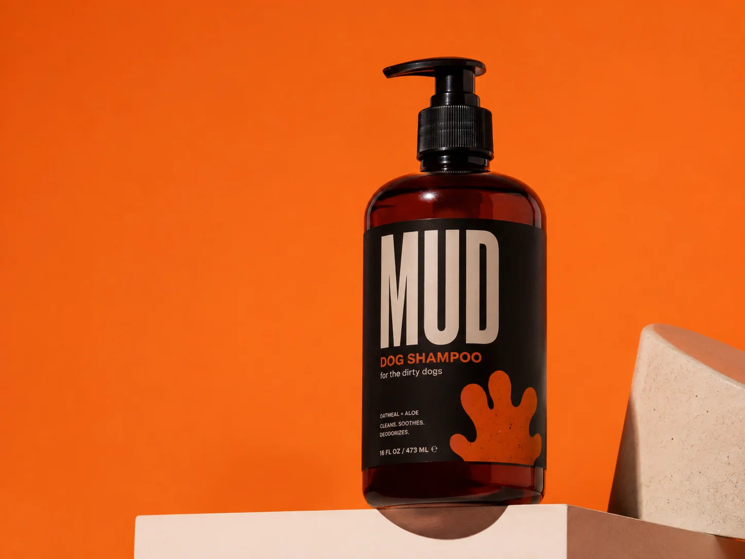 MUD dog shampoo bottle on a vivid orange studio set
