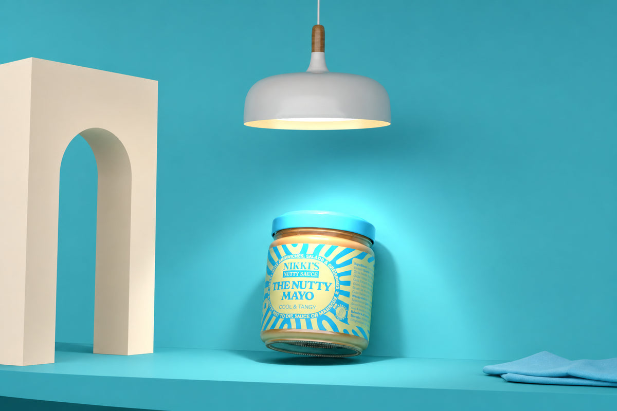 Nikki's Nutty Mayo jar under a pendant light in a blue editorial packaging mockup