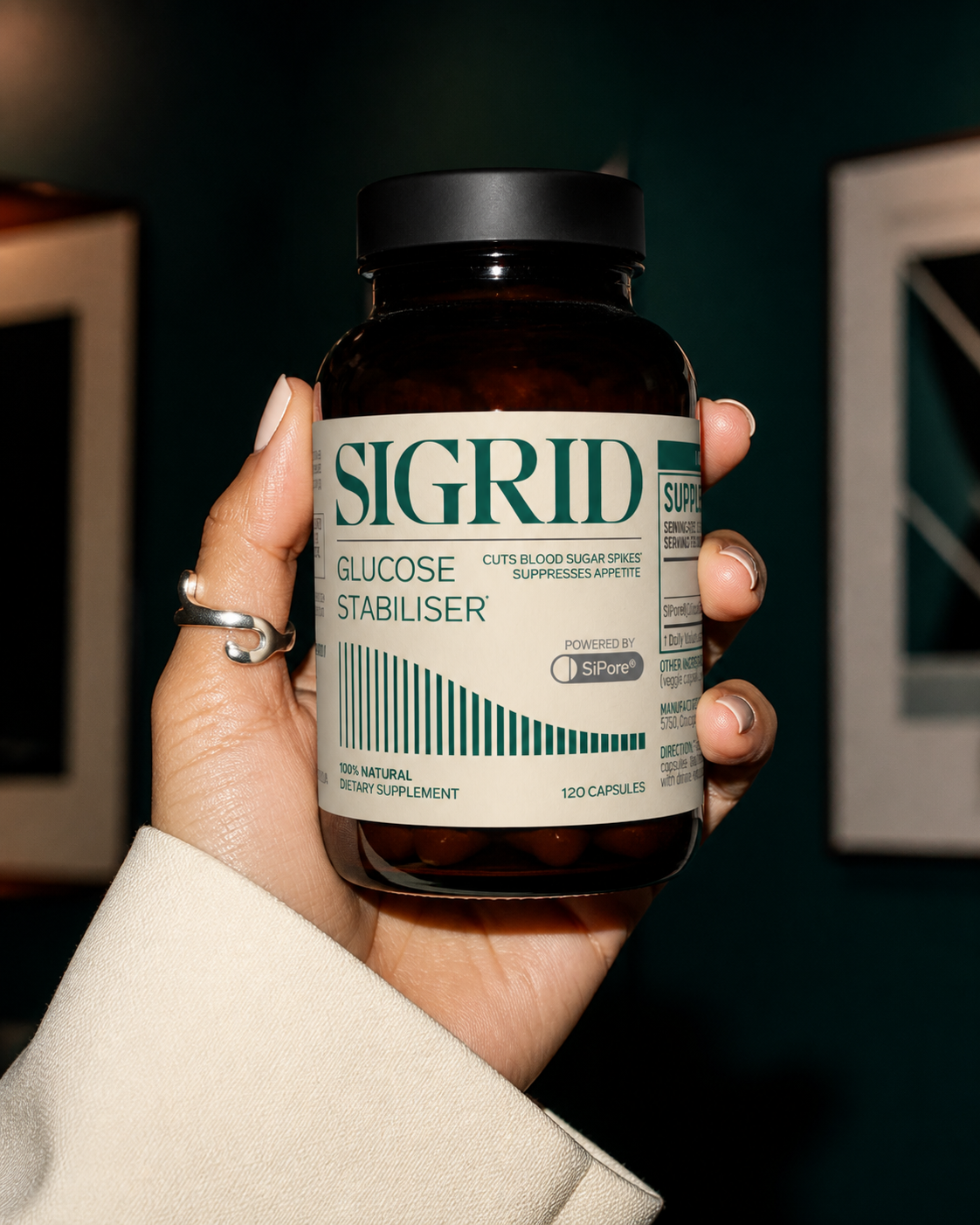 Adult woman's hand holding the SIGRID Glucose Stabiliser amber bottle in a flash-lit fashion editorial composition