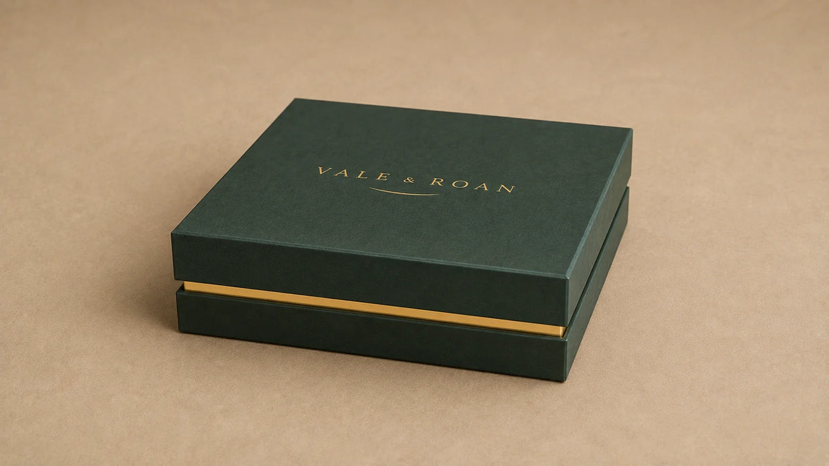 Closed dark green Vale & Roan dog collar presentation box with a gold wordmark on a warm beige surface